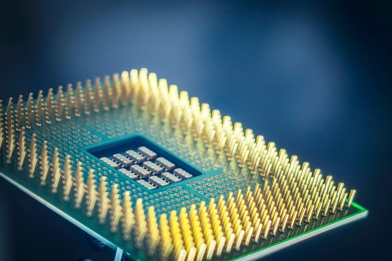 A computer processor chip with gold pins against a blue background