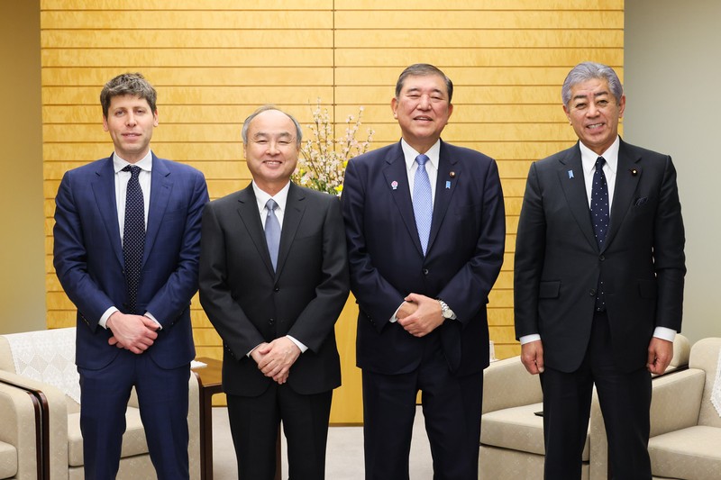 Four men in business suits standing in a formal meeting room with wooden paneling