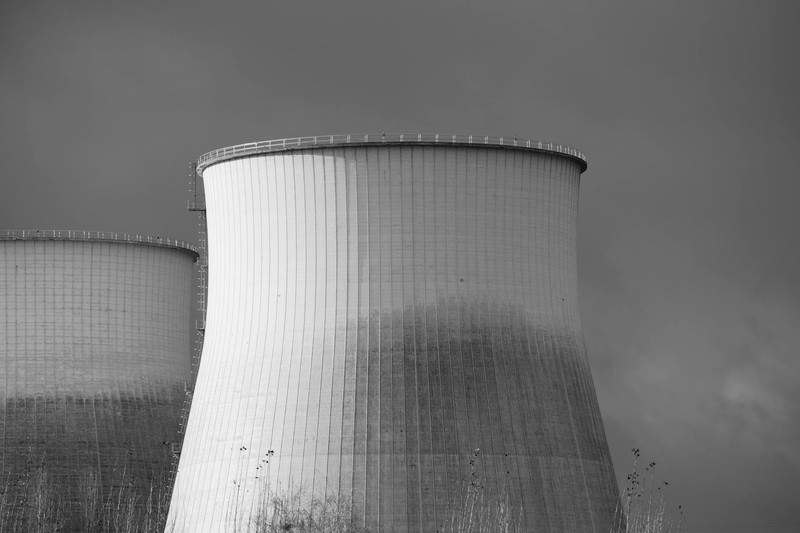 Black and white photo of nuclear power plant cooling towers under a dark overcast sky