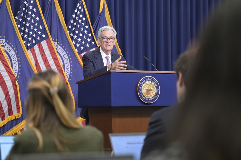Federal Reserve Chair Jerome Powell speaking at a press conference behind the official podium with U.S. and Federal Reserve flags