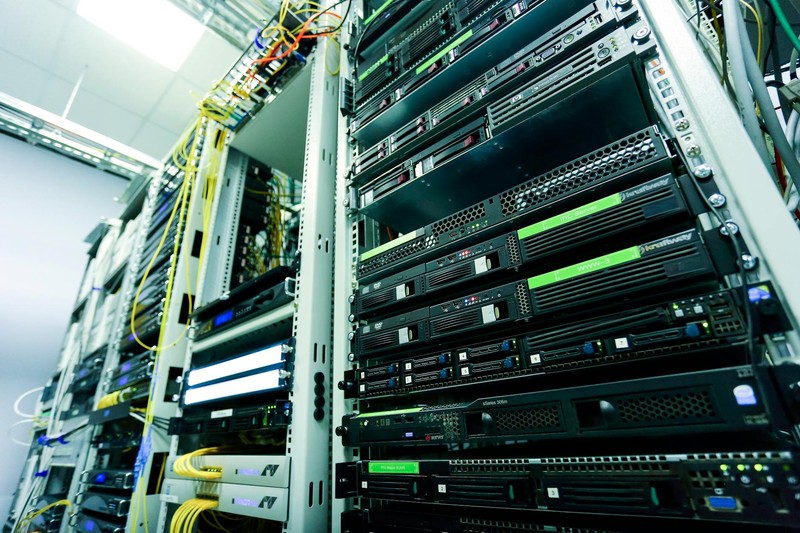 Server racks with network cables and green status lights inside a high-tech data center