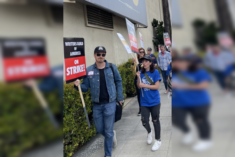 SAG-AFTRA members on a picket line during the actors' strike, holding union strike signs outside a studio building