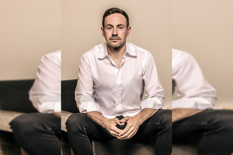 Portrait of entrepreneur Ryan Cohen in a white dress shirt against a beige background