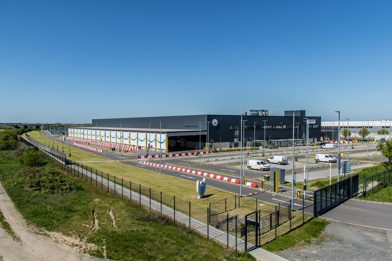 Aerial view of a large Amazon logistics center with surrounding roads and green space