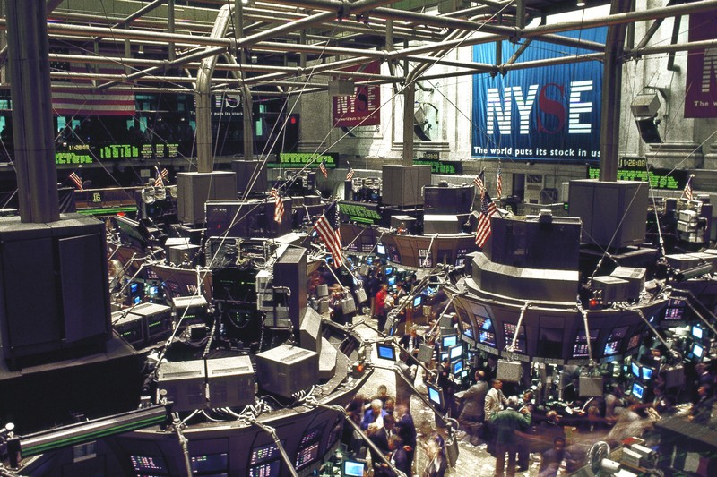 Interior of the New York Stock Exchange trading floor with traders, monitors, and prominent NYSE signage