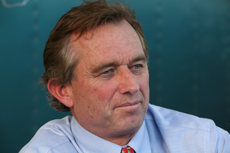 Robert F. Kennedy Jr. in a professional portrait wearing a light blue shirt and red tie