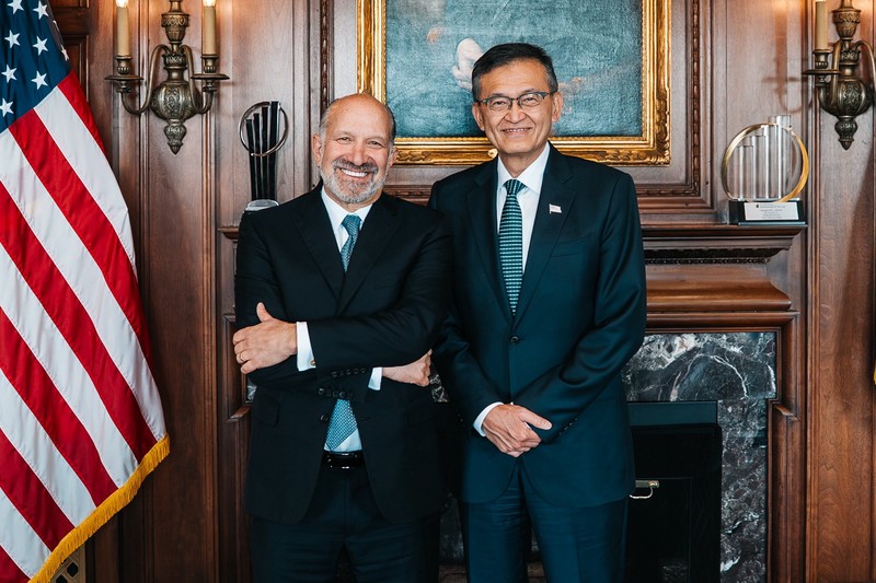 US Commerce Secretary Howard Lutnick and Intel CEO Lip-Bu Tan pose together in a formal government setting with an American flag