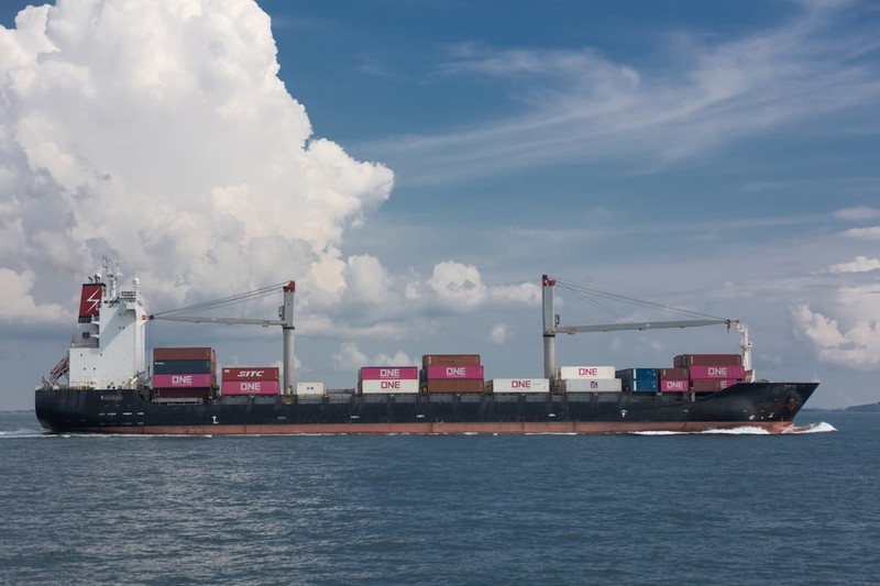A container ship sailing on open ocean under a partly cloudy sky