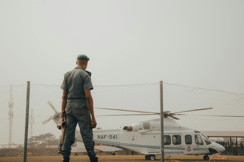 A Nigerian Air Force helicopter and military officer at an airfield