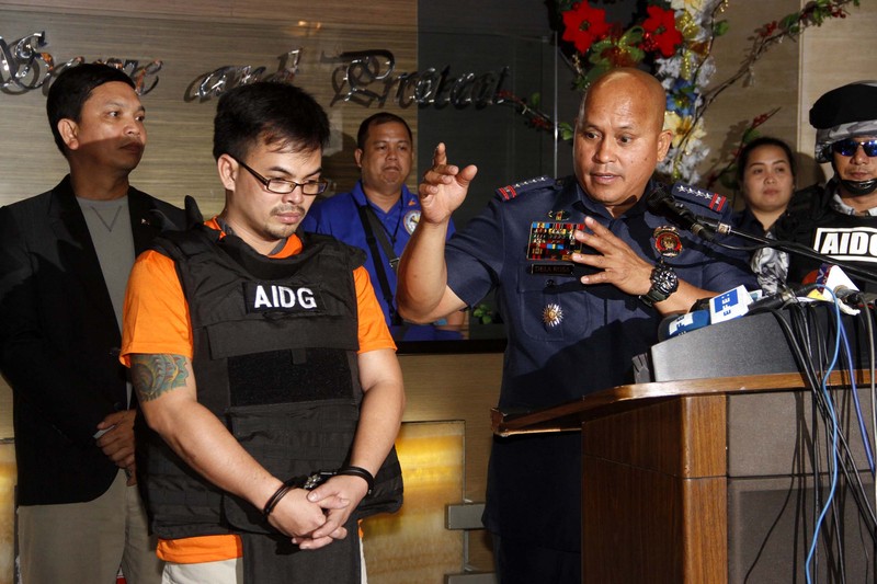 Philippine National Police Chief Ronald Dela Rosa speaks at a press conference alongside a detained suspect wearing an Anti-Illegal Drugs Group vest